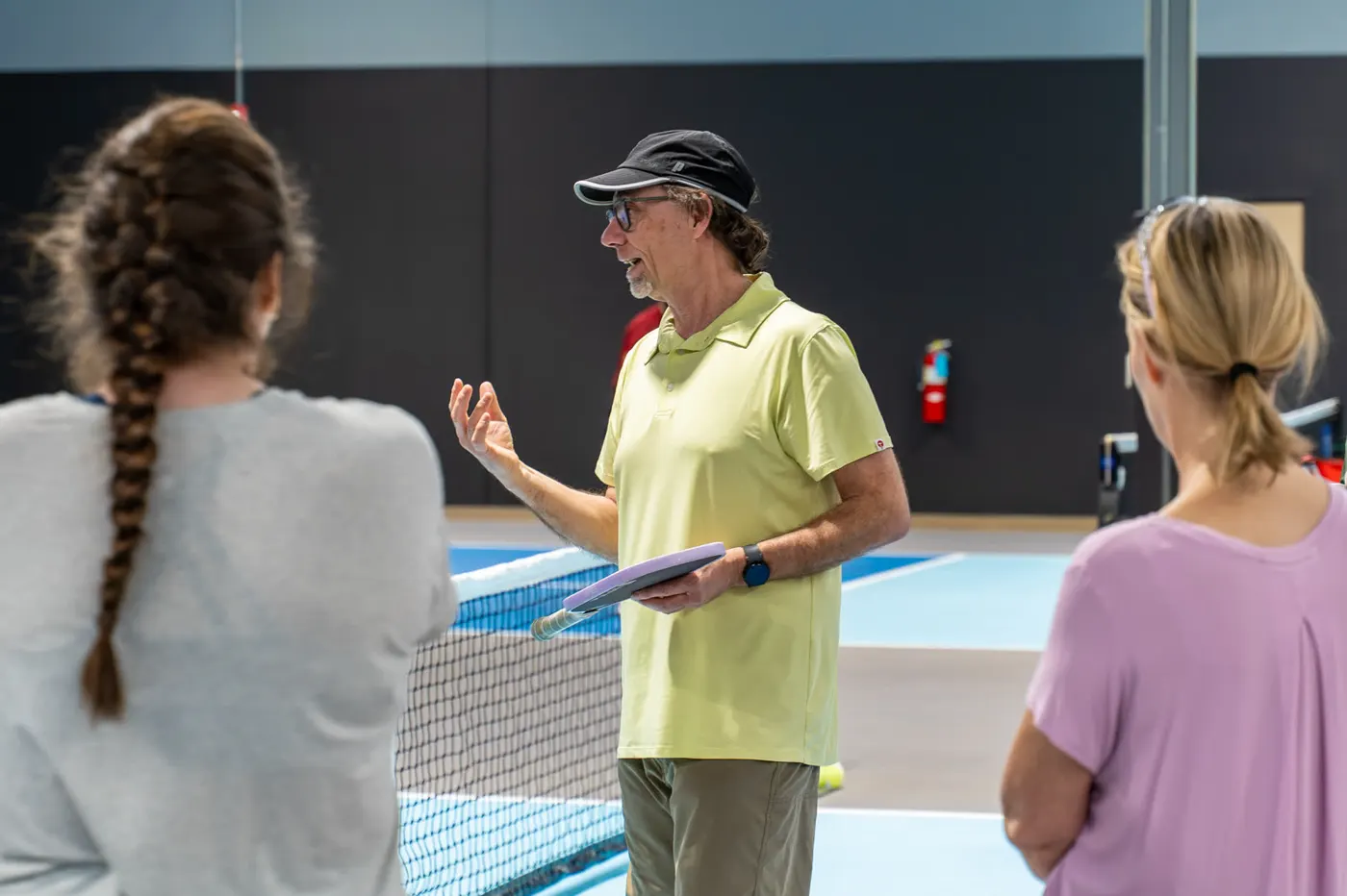 A coach working with a pickleball player on an indoor court.