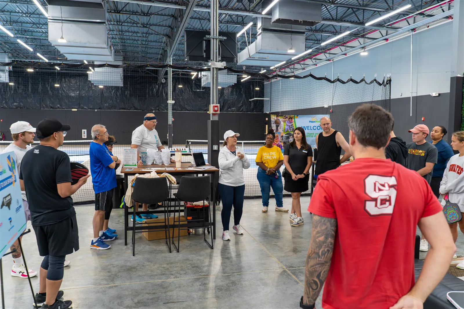 A Carolina Pickleball Club event floor with players gathered for announcements