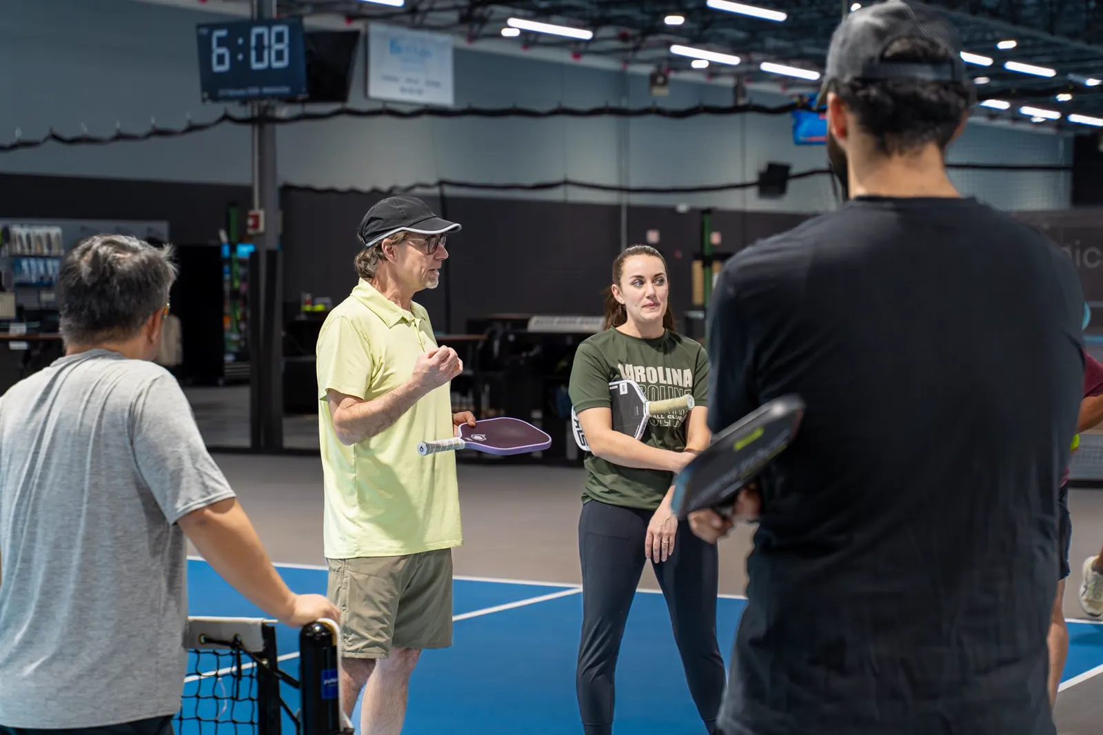 A coach and players talking through a pickleball drill on court