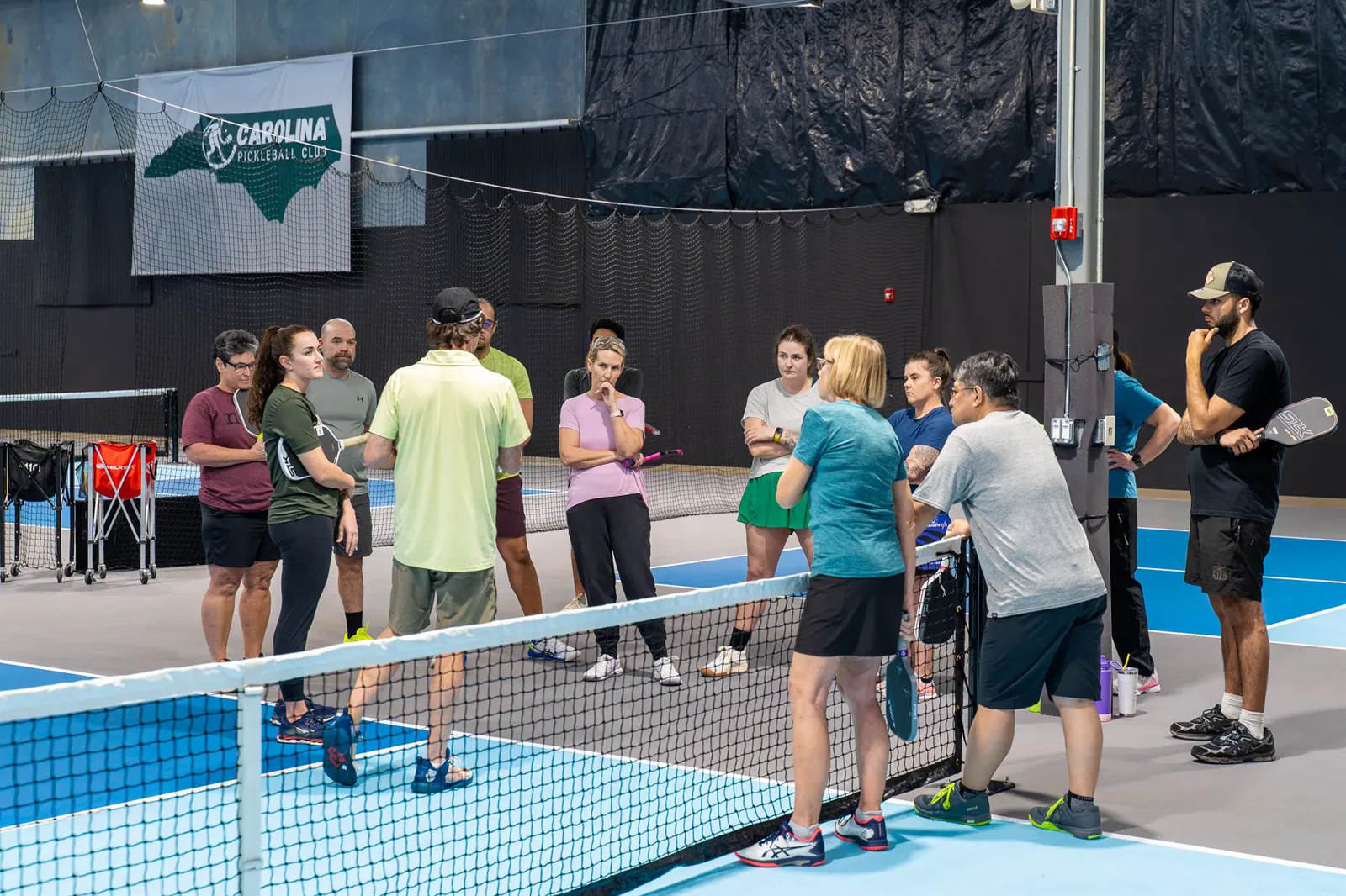 A small group gathered for pickleball instruction on an indoor court