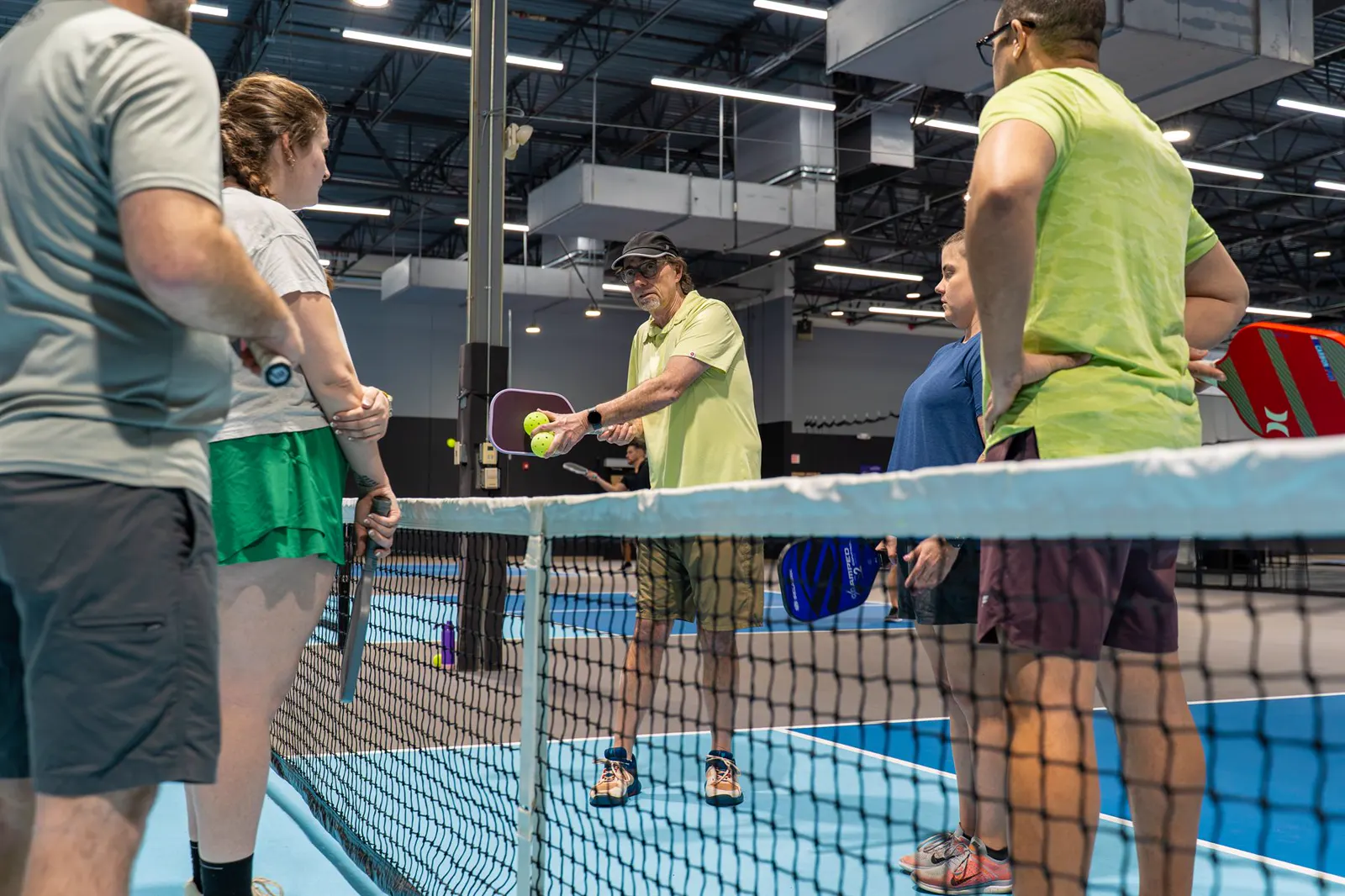 Players receiving pickleball instruction beside the net