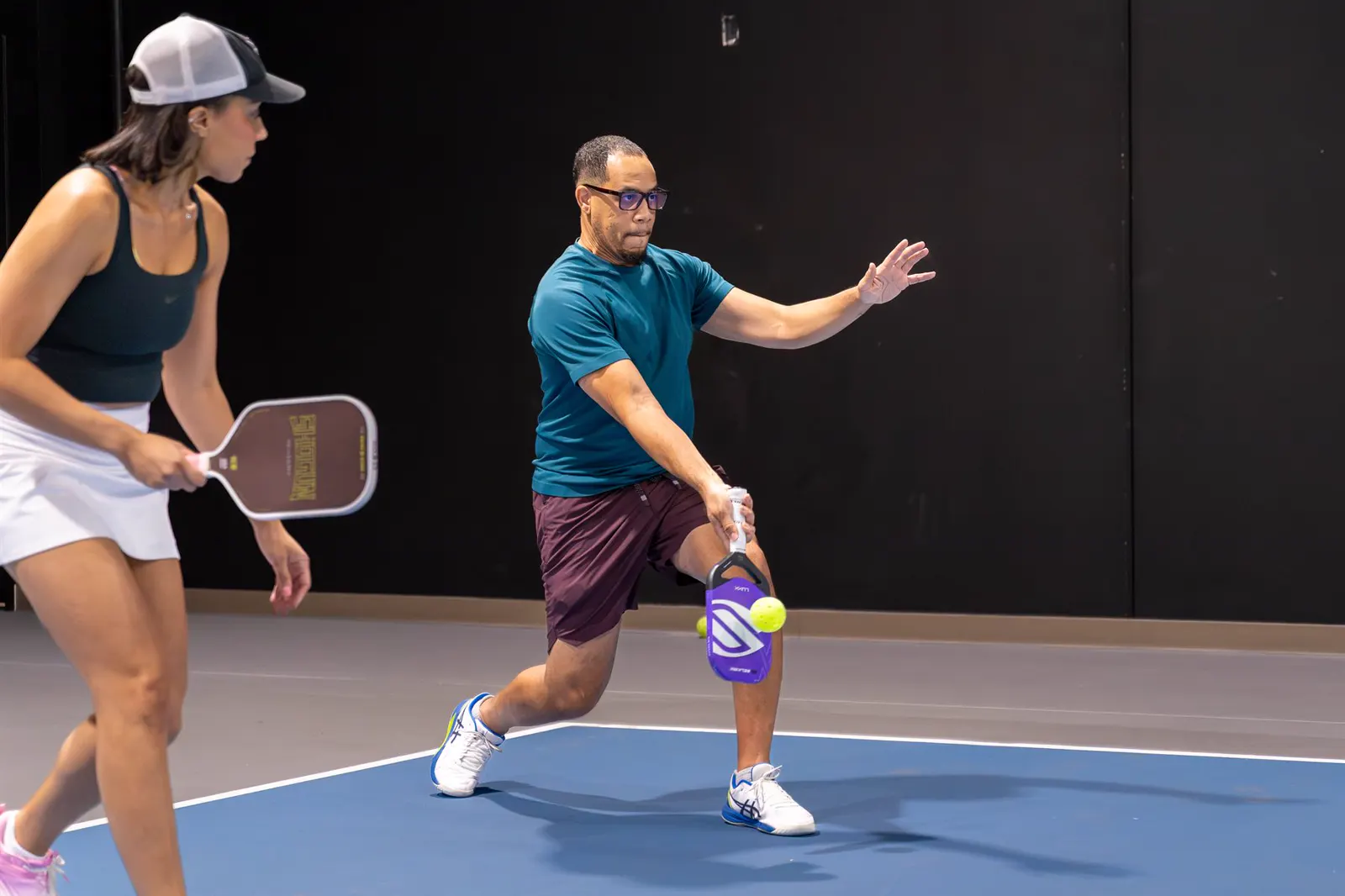 Players moving through a casual doubles point on an indoor court
