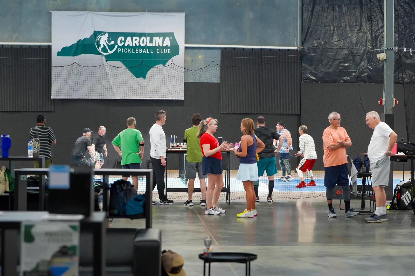A busy Carolina Pickleball Club event scene with players gathered around the courts